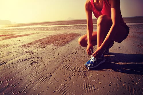 woman runner tying shoelace before running on beach-img-blog